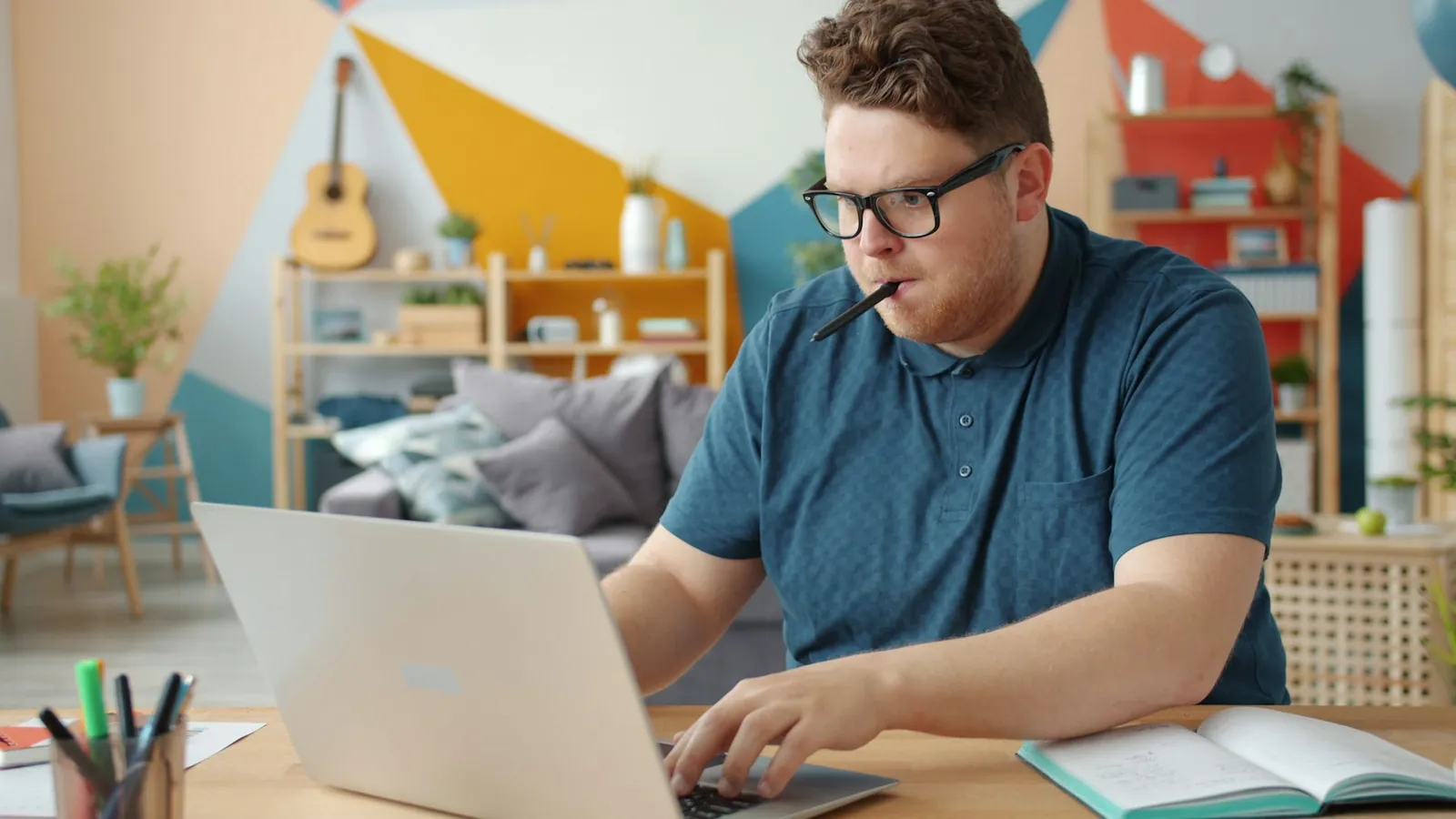 A learner studying with a laptop and an open notebook at a desk