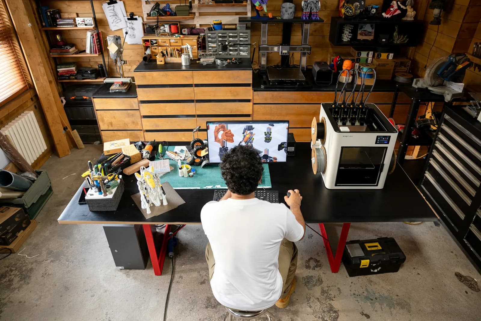 An engineer working with CAD beside a 3D printer
